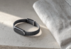Bracelet santé sans écran posé sur une surface claire, à côté d'une montre connectée